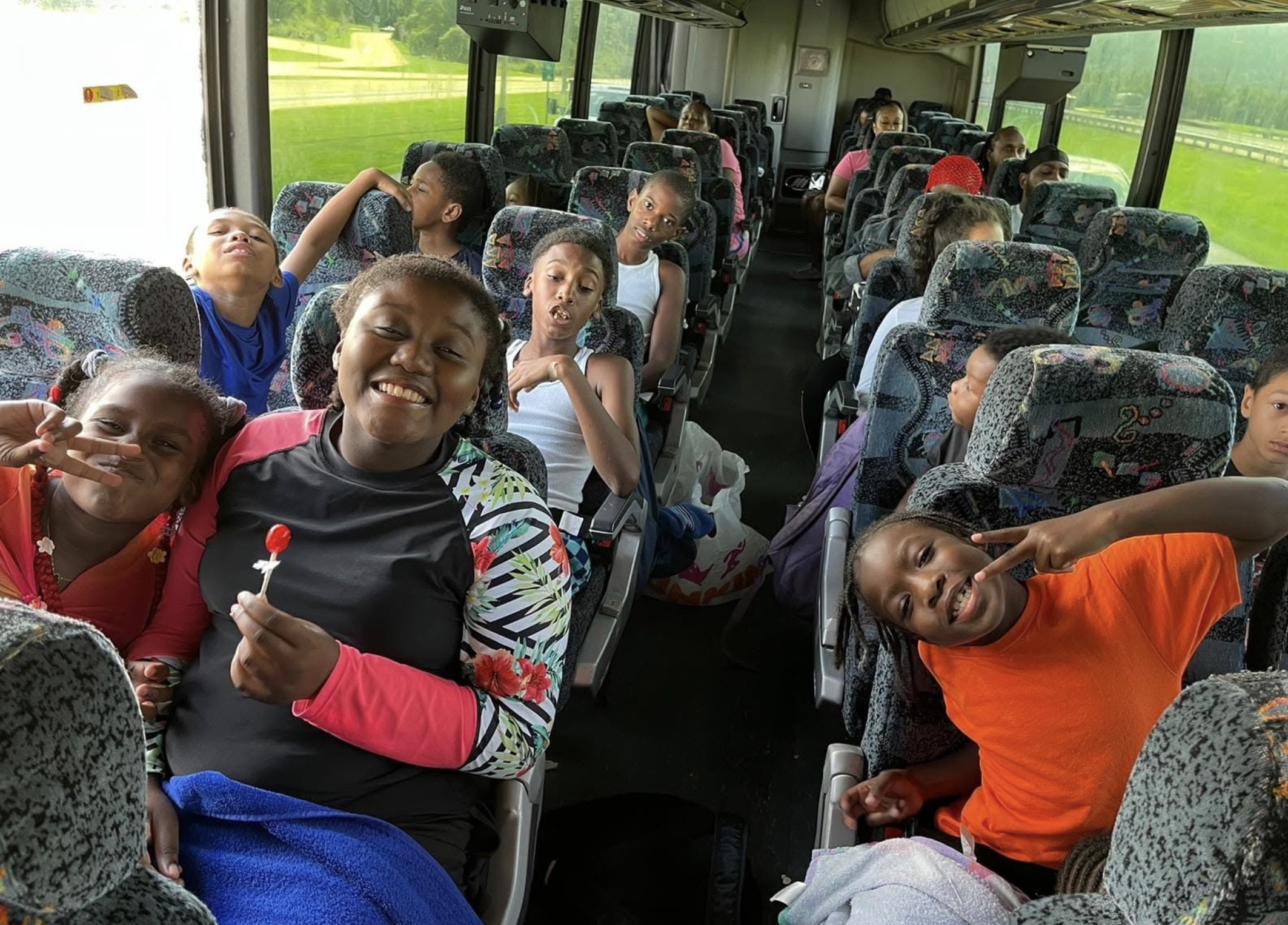 Children and caregivers smiling together on a daycare field-trip bus