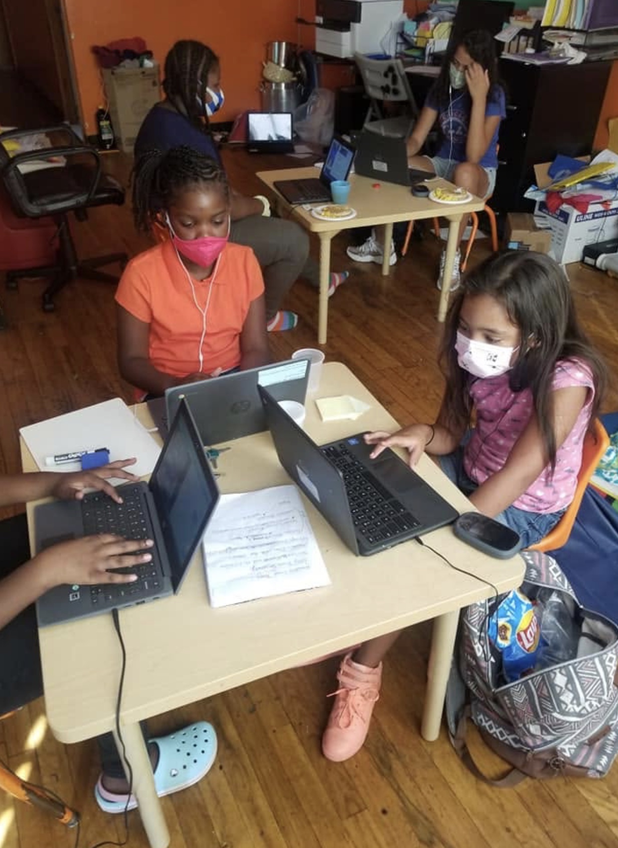 School-age children working on laptops with adult support