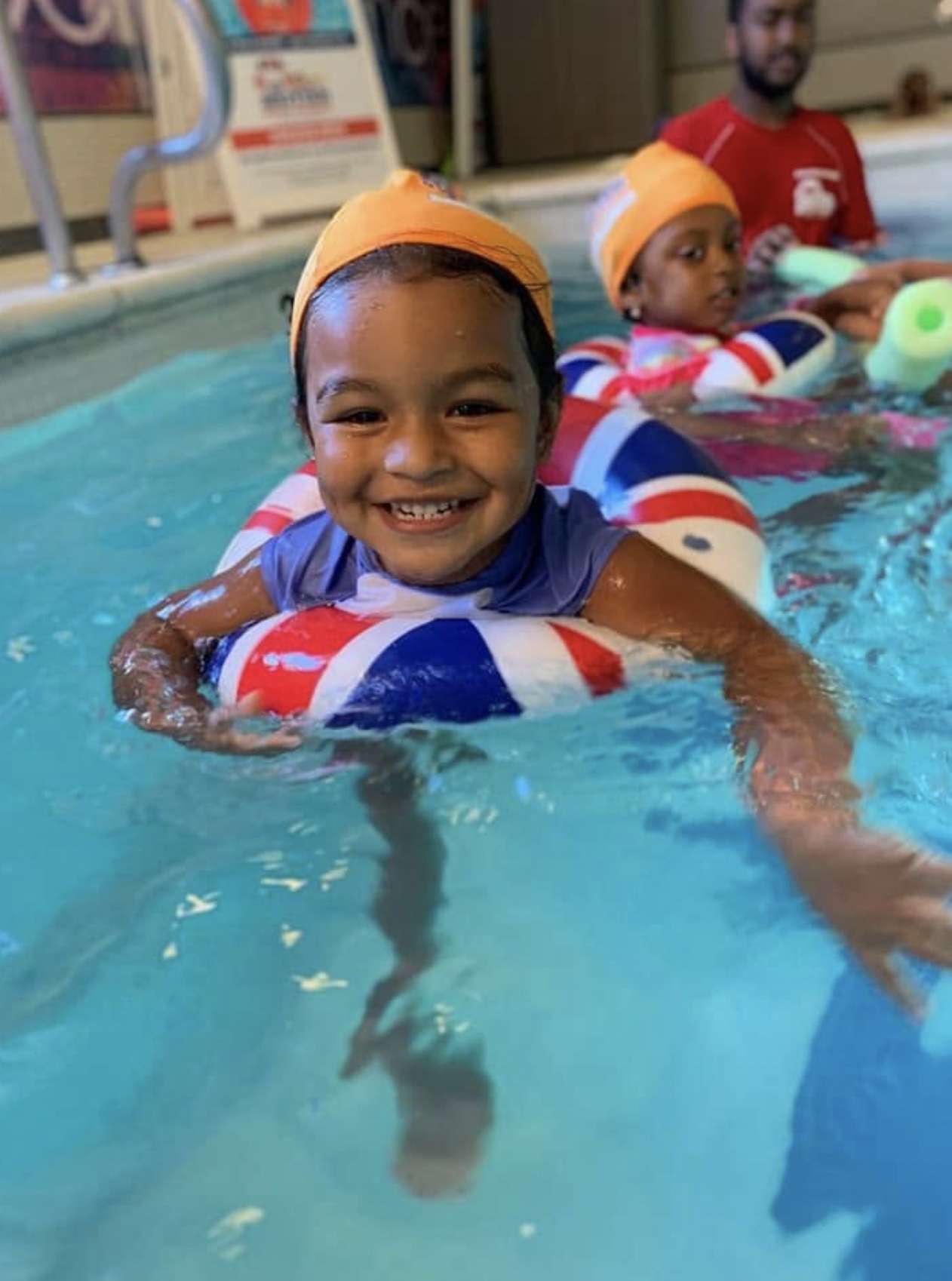A smiling young child enjoying a supervised swimming lesson
